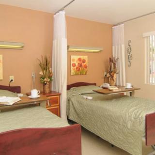 A hospital room with two neatly made beds, divided by a curtain, designed for patient care and comfort.