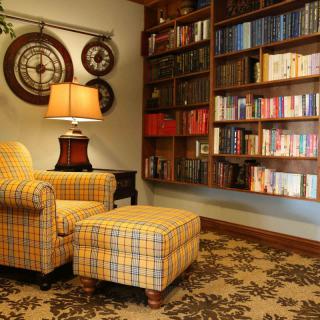 A cozy reading corner with a plaid armchair and a well-stocked bookshelf.