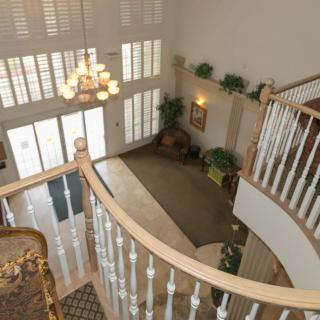 A spacious foyer with a grand staircase, chandelier, and large windows.