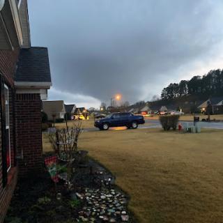 A looming storm clouds over a quiet residential neighborhood during twilight.