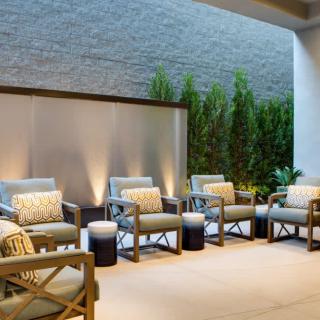A stylish outdoor seating area with comfortable chairs, cushions, and ambient lighting.