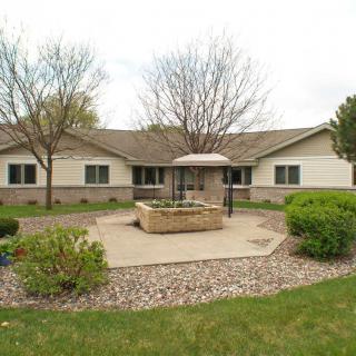 A residential building with well-maintained landscaping and a fountain in the front yard.