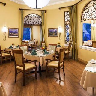 An elegant dining room with neatly arranged tables and chairs, featuring sophisticated decor and warm lighting.