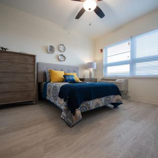 Cozy bedroom with modern decor and ample natural light from large windows.