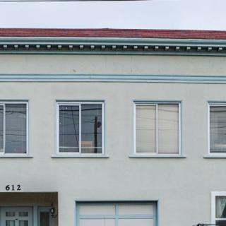 A two-story building with a flat roof, featuring multiple windows and a simple facade.