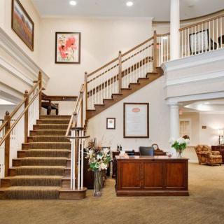 A spacious and elegant lobby with a grand staircase and reception desk.
