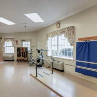 A rehabilitation room equipped with parallel bars and exercise equipment under bright lighting.
