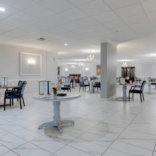 A modern restaurant dining area with white decor and neatly arranged tables and chairs.