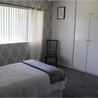 A minimalist bedroom with a bed, chair, and wardrobe.