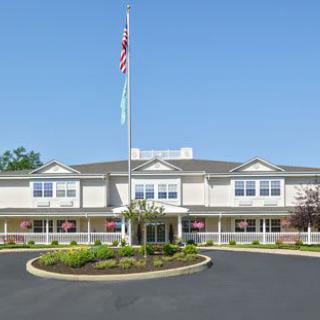 A large building with a flagpole and landscaped entrance under a clear blue sky.