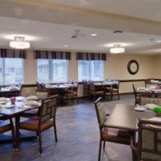 A neatly arranged dining area with multiple tables and chairs, featuring large windows and ambient lighting.