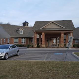 A modern residential building with a welcoming entrance and a parked silver car in the foreground.