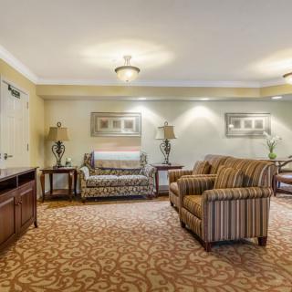 A cozy living room with sofas, decorative lamps, and patterned carpeting.