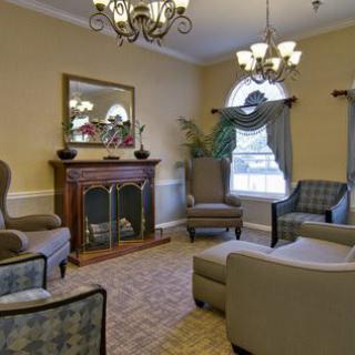 A cozy living room with elegant furniture and a fireplace, featuring chandeliers and ample seating.