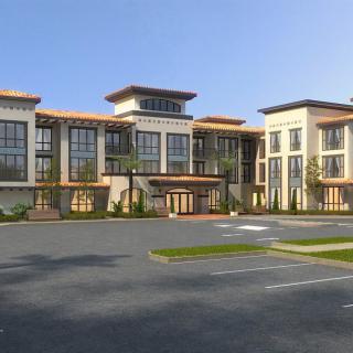 A modern commercial building with large windows and a spacious parking lot.