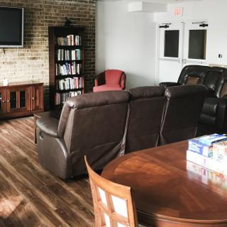 A cozy living room with a large couch, a bookshelf, and a television.