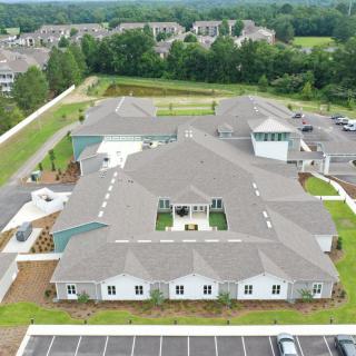 An aerial view of a large building surrounded by green spaces and parking areas.