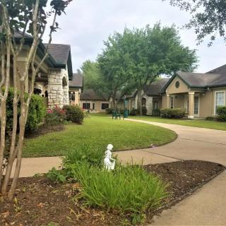 A peaceful neighborhood with well-maintained landscaping and trees lining the sidewalk.
