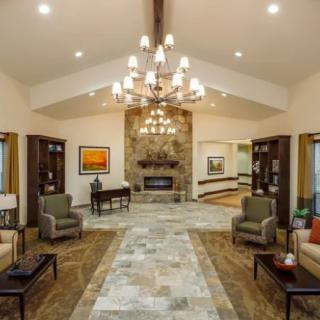 A spacious and elegantly designed living room featuring a central chandelier, a stone fireplace, and comfortable seating.