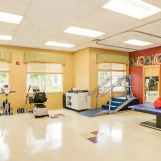 A bright rehabilitation gym with various exercise equipment.