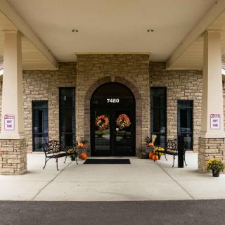 A building entrance with a stone facade and arched doorway, featuring outdoor benches and seasonal decorations.