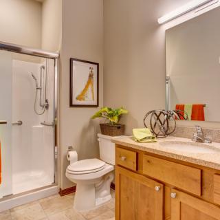 A modern bathroom featuring a glass-enclosed shower, wooden cabinets, and decorative elements.