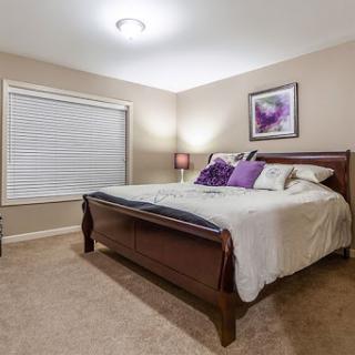 A cozy bedroom featuring a comfortable bed with purple accents and soft lighting.