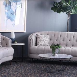 A modern living room featuring elegant sofas, a round coffee table, abstract artwork, and a large potted plant.