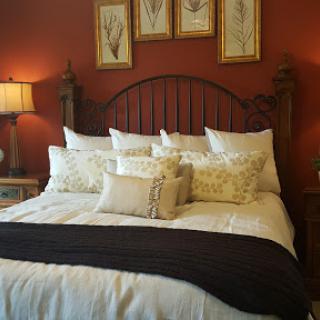 A beautifully styled bedroom featuring a cozy bed with decorative pillows and framed wall art.