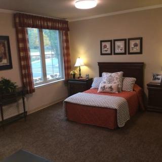 A cozy bedroom with a neatly made bed, soft lighting, and a window bringing natural light.