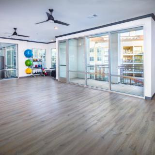 Spacious and bright yoga studio with wood flooring and fitness equipment.