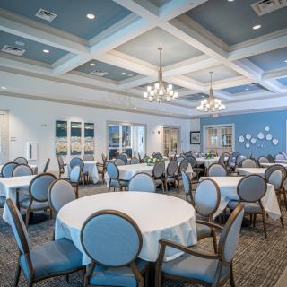 An elegant banquet hall with round tables and chandeliers, ready for an event.
