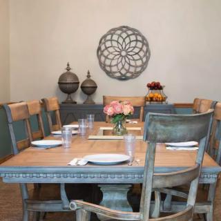 A beautifully set dining room table with rustic chairs and elegant wall decor.