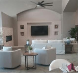 A modern living room with white sofas, armchairs, a large television, and stylish decor.
