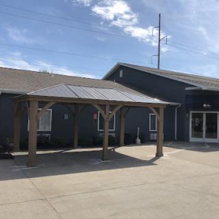 A modern exterior view of a building with outdoor seating and clear skies.