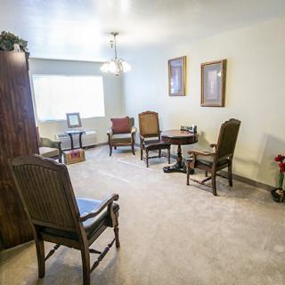 A cozy living room with several chairs, a small table, and abundant natural light.