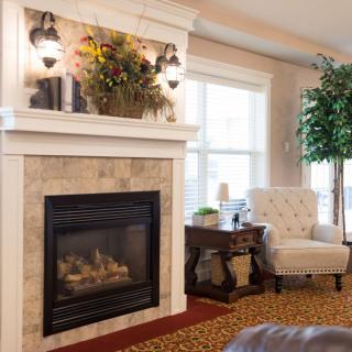 A cozy living room featuring a fireplace, elegant armchair, and decorative elements.