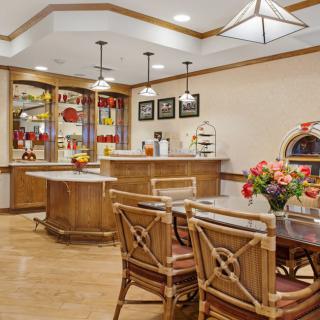 A cozy kitchen and dining area featuring wooden furniture, modern lighting, and a vibrant flower arrangement.