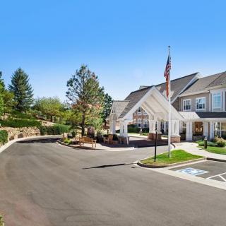 A large suburban building with a driveway, surrounded by landscaped greenery and an American flag flying at the entrance.