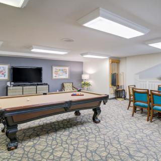 A well-furnished game room featuring a pool table and seating area with a television.