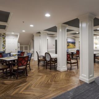 A well-decorated dining area with multiple tables and chairs, featuring elegant flooring and lighting.