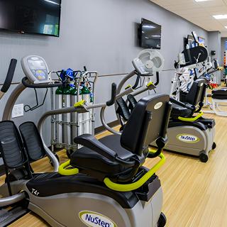 A well-equipped gym with exercise machines and televisions.