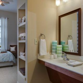 A cozy bathroom connected to a bedroom, featuring a sink with towels and stylish decor.
