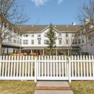 A residential building with a white picket fence and clear blue sky.