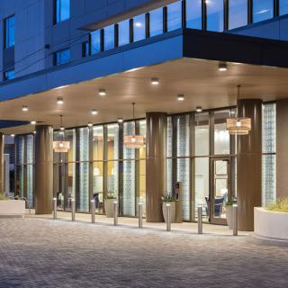 A modern building entrance illuminated at night with glass doors and bright lights.
