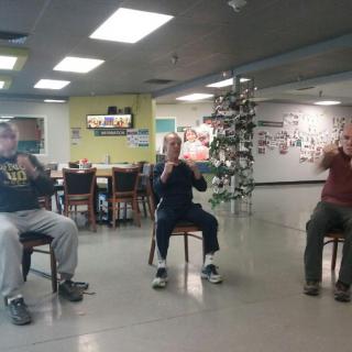 A group of seniors participating in a chair-based exercise class at a community center.
