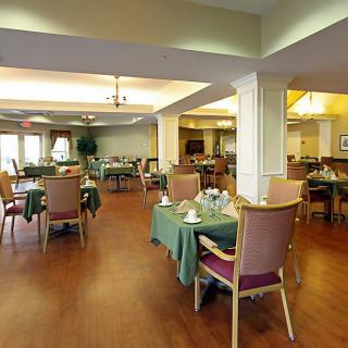 A spacious dining area with neatly arranged tables and chairs on a wooden floor.