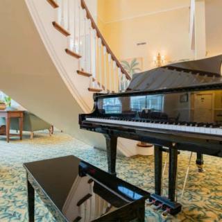Elegant grand piano placed in a stylish living room beside a curved staircase.