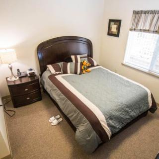 A cozy bedroom with a neatly made bed, nightstand, and lamp.