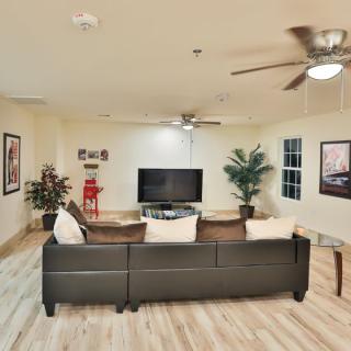 A modern living room with a large sofa, TV, and ceiling fans.